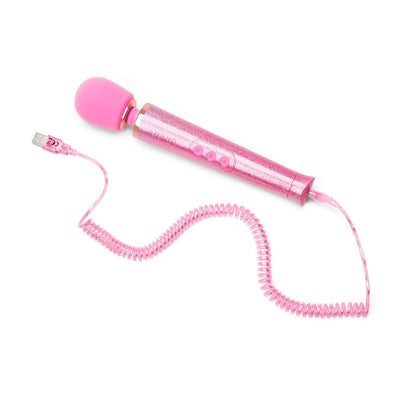 Pink glittery Le Wand Petite massager wand with coiled USB charging cable on white background.