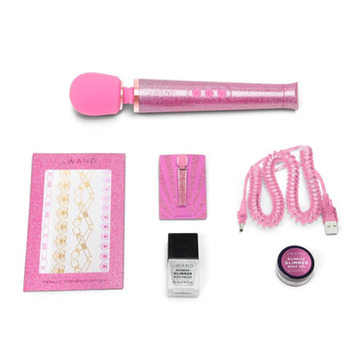 Le Wand All That Glimmers Set with pink glitter wand, USB charging cable, nail polish, body gel, enamel pin, and pleasure guide.