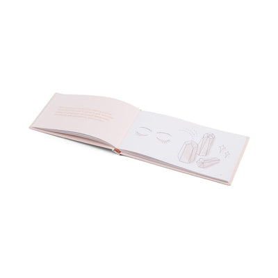 Open hardcover guidebook with simple line drawings of crystals and closed eyes on white pages