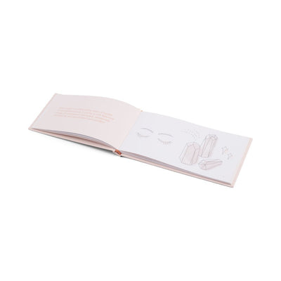 Open booklet with soft pink pages featuring delicate line drawings of closed eyes and crystals on a white background