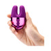 Hand holding a compact Le Wand Double Vibe with purple silicone bunny ears and pink metallic body with control buttons.