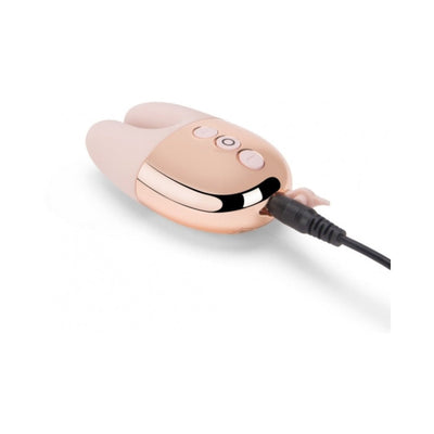 Le Wand Double Vibe in soft pink with rose gold accents shown charging with USB cable connected.