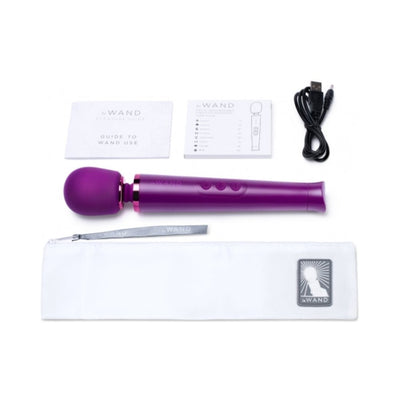 Purple Le Wand Petite rechargeable massager with USB charging cable, user guides, and white storage pouch on white background.