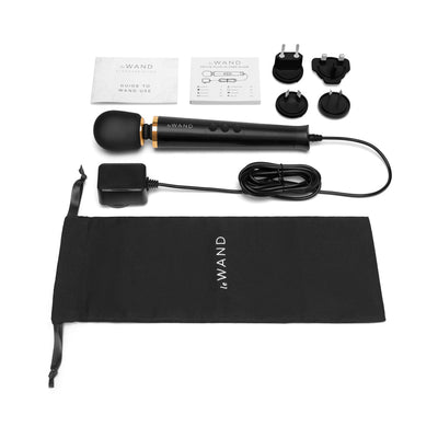 Le Wand Powerful Petite Plug-in massager with power cord, four plug adapters, user guides, and black storage pouch on white background.