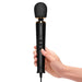 Hand holding black Le Wand Powerful Petite Plug-in massager with flexible silicone head and control buttons on handle.