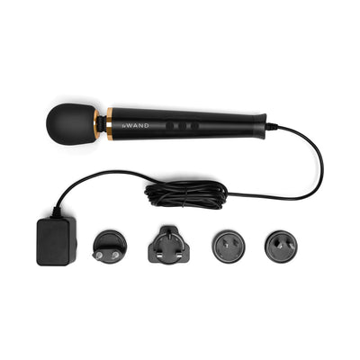 Le Wand Powerful Petite Plug-in massager in black with gold accents, long cord, and four interchangeable plug adapters.