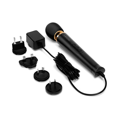 Le Wand Powerful Petite Plug-in massager in black with gold accent, long cord, and multiple international plug adapters.