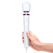 Hand holding white Le Wand Powerful Petite Plug-in massager with flexible neck and control buttons on handle.