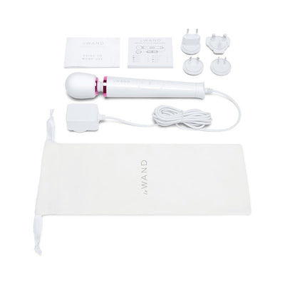 Le Wand Powerful Petite Plug-in massager with 8-foot cord, multiple plug adapters, user guides, and storage pouch on white background.