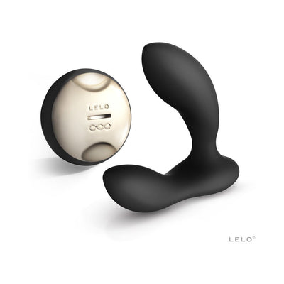 Black rechargeable prostate massager with curved ergonomic design and a sleek gold-toned wireless remote control.