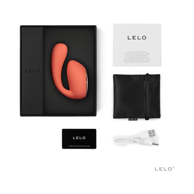 Lelo Ida Wave Dual Stimulator in coral with black storage pouch, USB charging cable, warranty card, and user manual in black box.