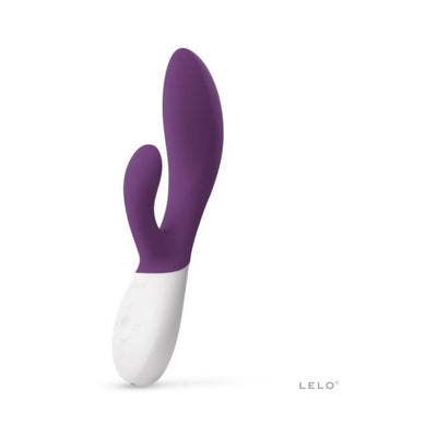 Purple and white dual stimulator with ergonomic design and silicone texture by LELO, standing upright on white background.