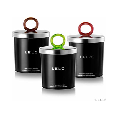 Three black Lelo massage candles with silver lids and colorful ring handles in brown, green, and red, each labeled with a different scent.