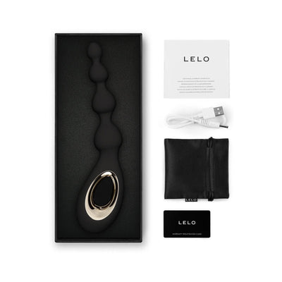 Lelo Soraya Anal Beads in black with gold accent, USB charging cable, storage pouch, user manual, and warranty card in packaging.