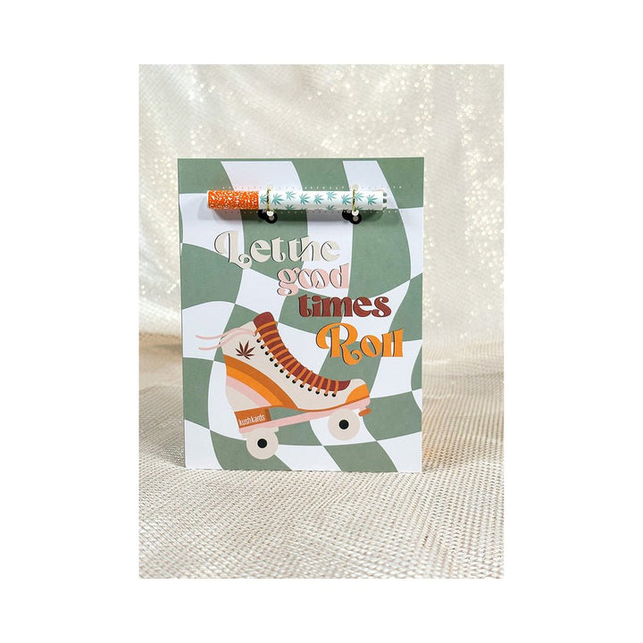 Retro-style greeting card with a roller skate design and attached patterned one hitter pipe on a green and white checkered background.