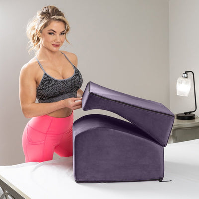 Woman demonstrating the plum-colored Liberator Flip Ramp, a versatile foam wedge that transforms from ottoman to curved ramp.