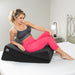 Woman in athletic wear reclining on black Liberator Wedge/Ramp Combo cushion on a bed with white sheets