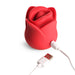 Red silicone rose-shaped clitoral stimulator with USB charging cable attached on white background.
