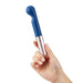 Hand holding a blue Love Not War Kama Head G-spot massager with a silver base against a white background.