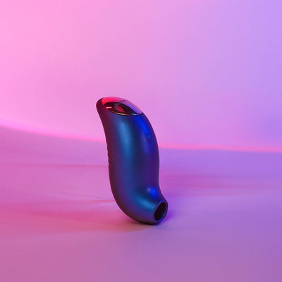 Compact iridescent silicone clitoral stimulator with ergonomic curved design and LED display on pink and purple gradient background.