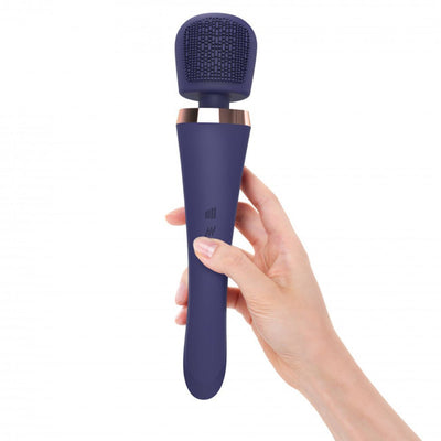 Hand holding a midnight indigo silicone wand stimulator with textured head and rose gold accent.