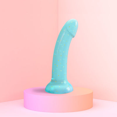 Curved pastel blue silicone toy with gold star glitter and suction base displayed on a pink pedestal.