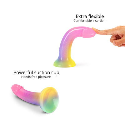 Rainbow-colored curved silicone dildo with glitter and strong suction cup base shown flexible and upright.