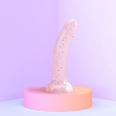 Pastel pink curved silicone toy with multicolored star glitter and suction base on a round pink pedestal.