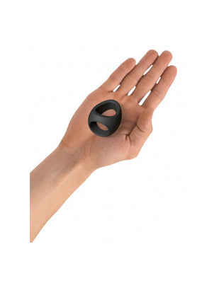 Hand holding a black double silicone cockring with two openings, designed for comfort and flexibility.