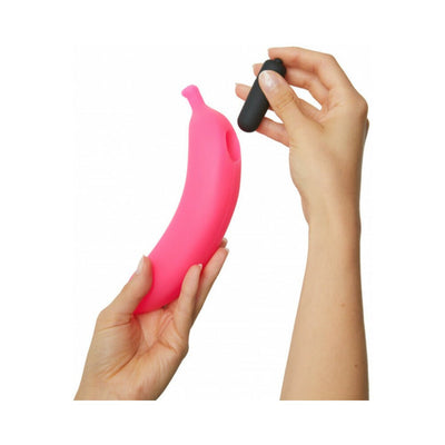Hands holding a pink silicone vibrator shaped like a banana and a small black removable bullet vibrator.