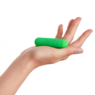 Hand holding a small, green, compact bullet vibrator with a smooth, rounded design.