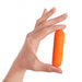 Hand holding a compact, bright orange, rechargeable bullet vibrator with a power button on top.