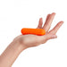 Hand holding a compact, bright orange rechargeable bullet vibrator with a smooth, rounded design.