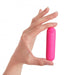 Hand holding compact pink bullet vibrator with power button on top against white background.
