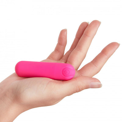 Compact bright pink bullet vibrator resting on an open hand against a white background.