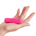 Compact bright pink bullet vibrator resting on an open hand against a white background.
