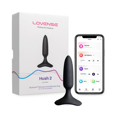 Lovense Hush 2 black silicone butt plug with flared base next to its packaging and smartphone showing app control interface.