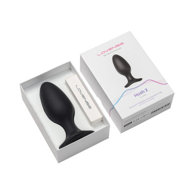 Lovense Hush 2 black silicone butt plug with flared base in white box packaging with charging cable.
