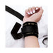 Close-up of a wrist secured in a black adjustable restraint cuff with soft lining on a white surface.