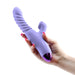 Hand holding a lavender Luxe Nova dual stimulator with a textured thrusting shaft and clitoral attachment.