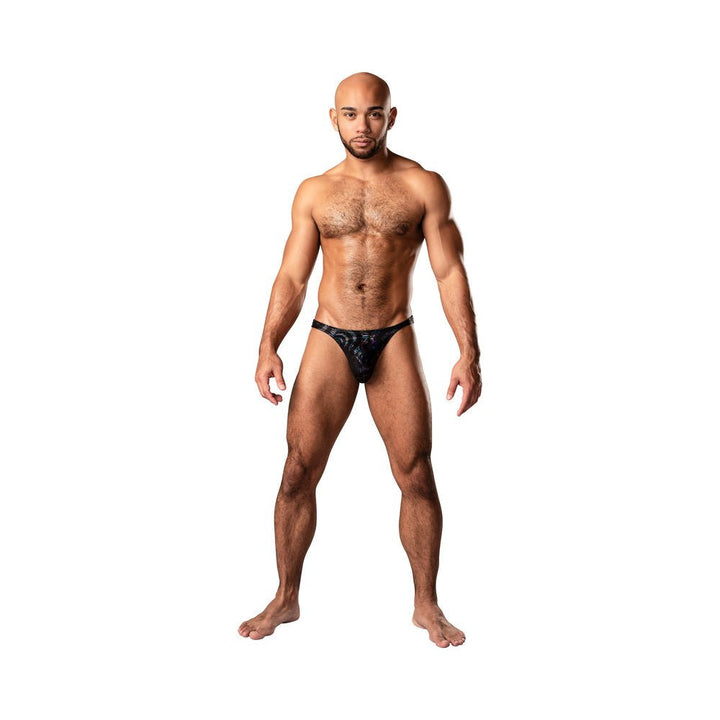 Male model wearing black iridescent metallic swirl print low-rise thong with slim t-back and contoured pouch on white background.