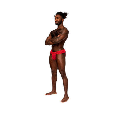 Man wearing a red lace skirt jock with sheer mesh pouch and ruffled waistband, standing with arms crossed on white background.