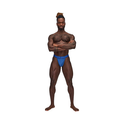 Muscular man wearing blue Male Power Sexagon Micro V Thong with branded waistband standing with arms crossed.