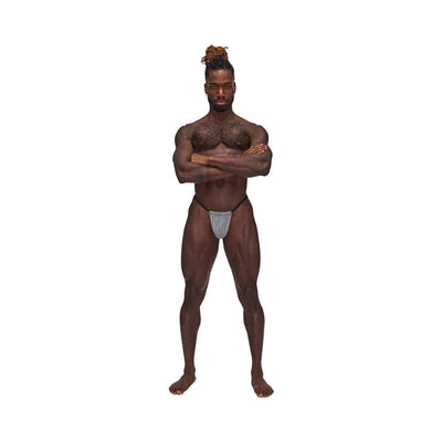 Muscular man wearing Male Power Sexagon Posing Strap with hexagon-print pouch and black elastic waistband on white background.