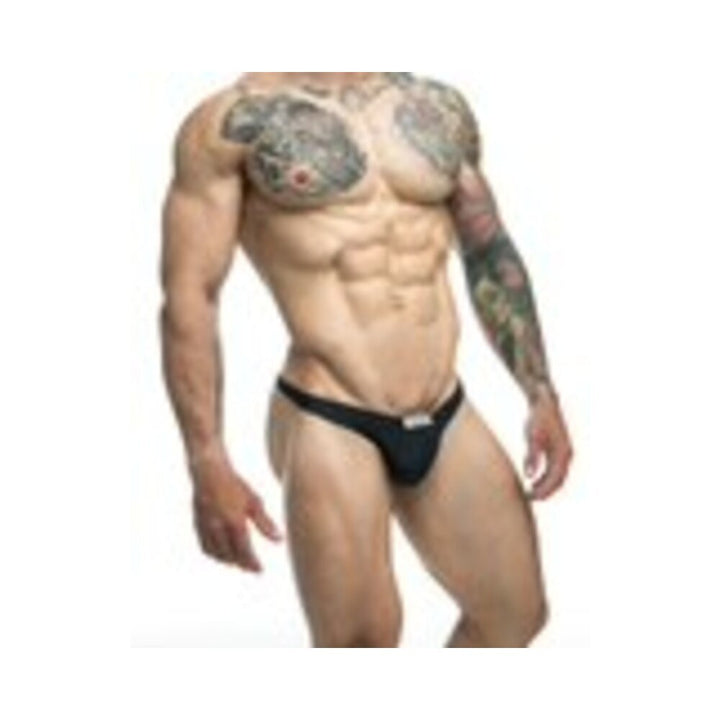 Muscular male model wearing black Malebasics Justin + Simon Classic Tanga underwear with tattooed chest and arm.