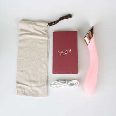 Pink curved Manto Touch Panel G-spot vibrator with USB charging cable, storage pouch, and instruction booklet on white background.