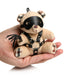 Hand holding a small beige teddy bear keychain wearing a black faux leather harness, eye mask, and holding a mini flogger.