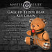 Plush brown teddy bear keychain with plaid accents, black vegan leather straps, chains, and a red ball gag accessory.