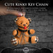 Small plush teddy bear keychain with cuffs, chains, and a red ball gag, held by a hand against a brick wall background.