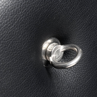 Close-up of a silver metal attachment ring mounted on black padded faux leather surface.